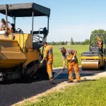 A road resurfacing crew at work on a country road in morning sun