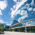 A glass administration building reflecting the sky