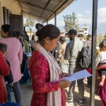 People of all ages queuing in warm daylight outside a civil registration office