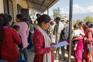 People of all ages queuing in warm daylight outside a civil registration office