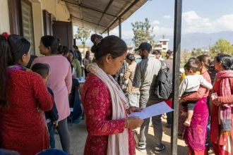 People of all ages queuing in warm daylight outside a civil registration office