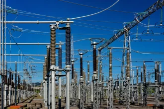 A high-voltage substation with steel lattice towers against a deep blue sky