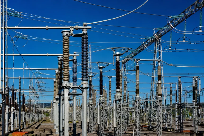 A high-voltage substation with steel lattice towers against a deep blue sky