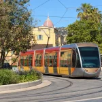 A modern low-floor tram rounding a curve on a sunny city street