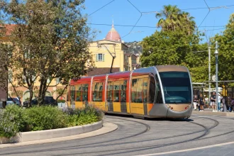 A modern low-floor tram rounding a curve on a sunny city street