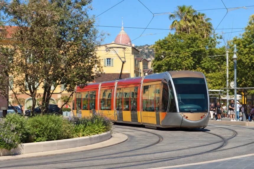 A modern low-floor tram rounding a curve on a sunny city street