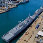 Aerial view of a naval dockyard with ships alongside a long quay