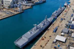 Aerial view of a naval dockyard with ships alongside a long quay