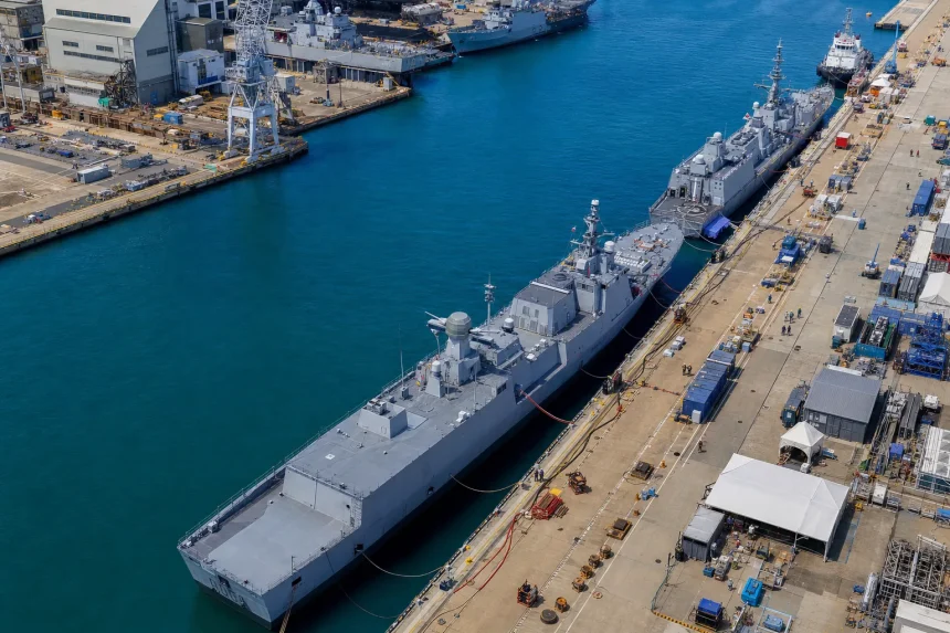 Aerial view of a naval dockyard with ships alongside a long quay