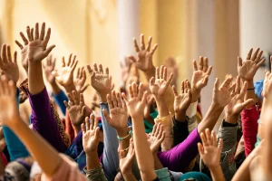 Macro of many raised hands as an overlapping pattern against a sunlit wall