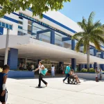 A public hospital exterior in strong sun with a blue and white tiled facade