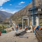 A highway bridge under construction across a wide Andean valley