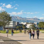 A large public university campus in bright daylight with mountains beyond