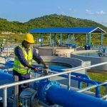A new water treatment works with blue pipework and concrete tanks in morning light