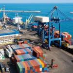 A working container port at midday with a gantry crane loading