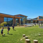 A contemporary school building in timber and glass with playing fields