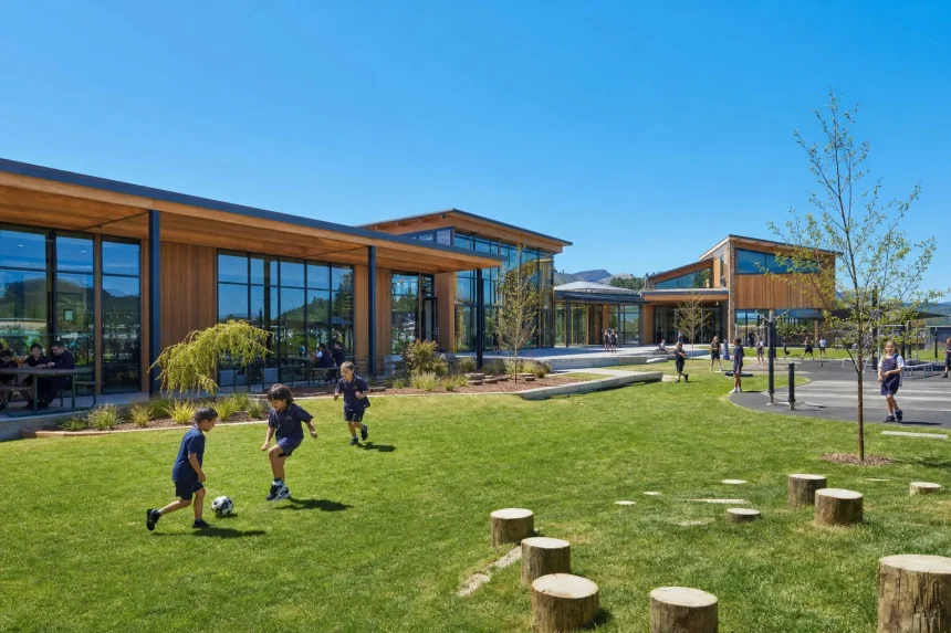 A contemporary school building in timber and glass with playing fields