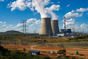 A large power station with cooling towers under a bright sky